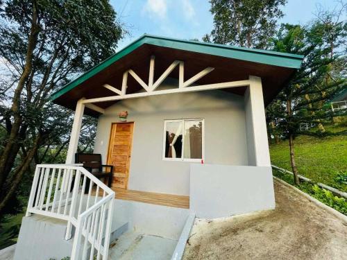 a small white house with a green roof at The PineHill Farm in Tanay