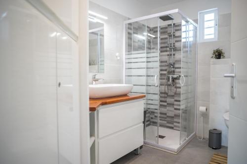 a white bathroom with a sink and a shower at Villa Le Manguier - Logement Marcus, Tout Confort in Goyave