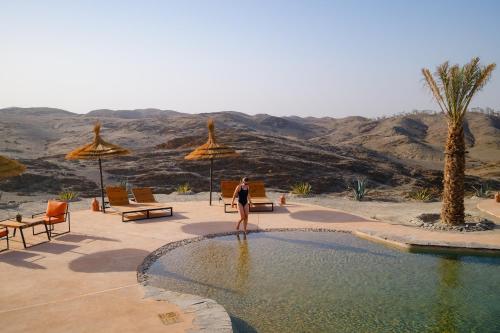 a woman standing in a swimming pool in the desert at SEVEN SAINTS Lodges in El Karia