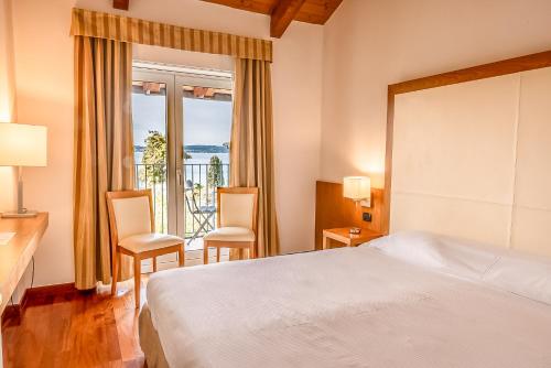 una camera d'albergo con un letto e un balcone di Hotel Mavino a Sirmione