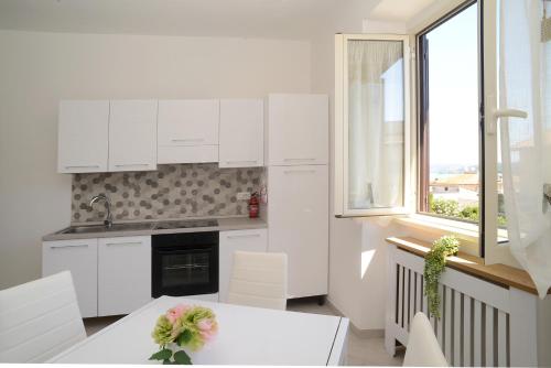 een keuken met witte kasten en een tafel en een raam bij GREGORIHOUSE in Anguillara Sabazia