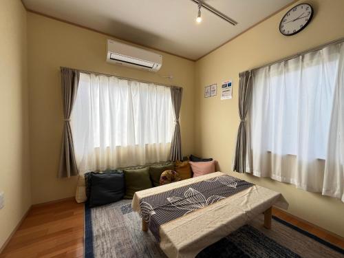 a bedroom with a couch and a clock on the wall at Guesthouse&Café Deep in Kōzushima