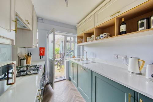 a kitchen with blue cabinets and white counter tops at 2 bed flat - SW London with parking in Teddington