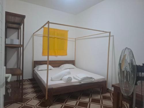 a bedroom with a canopy bed with a yellow towel at Bee Rooms Nosy be in Ambatoloaka