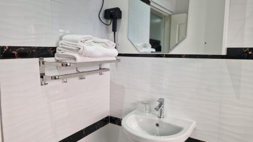 a white bathroom with a sink and a mirror at LENNON QUALITY Hotel in Umtali