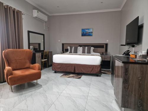 a bedroom with a bed and a chair and a television at LENNON QUALITY Hotel in Umtali