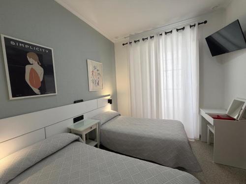 a hotel room with two beds and a television at Hostal Bahía in Cádiz