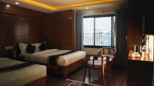 una camera d'albergo con due letti, una scrivania e una finestra di Hotel Mitra Inn a Kathmandu