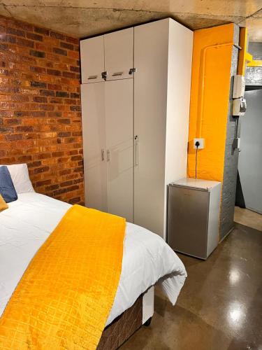 a bedroom with a bed and a brick wall at Craftsmanship Unit 235 in Johannesburg