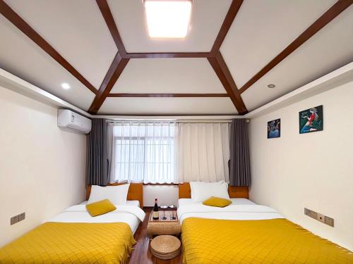 two beds with yellow cushions in a room at Yijingju Humanistic Inn in Zhangjiajie