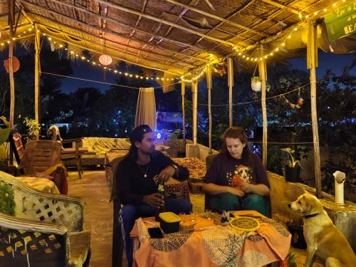een groep van drie personen die aan een tafel zitten met een hond bij JeeHaa Homestay in Alleppey