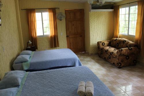 a bedroom with two beds and a couch and a chair at Hotel Valle Verde in Valle de Anton