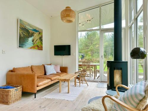 een woonkamer met een bank en een open haard bij Modern Peninsula Cabin With Panoramic View in Piggaboda