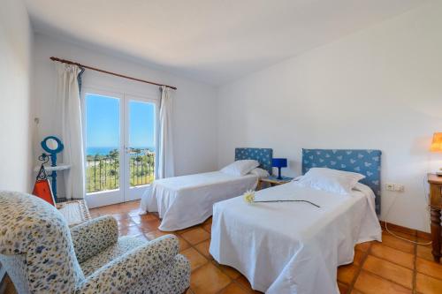 een kamer met 2 bedden, een stoel en een raam bij Can Roca in Illes Balears