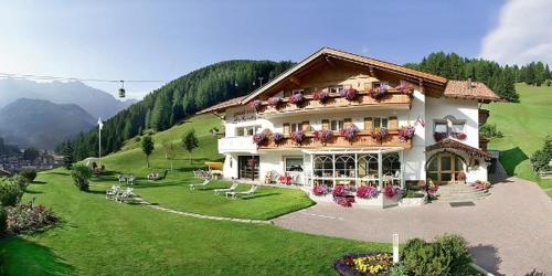 a large white building with flowers on the front of it at Garni la Bercia in Selva di Val Gardena