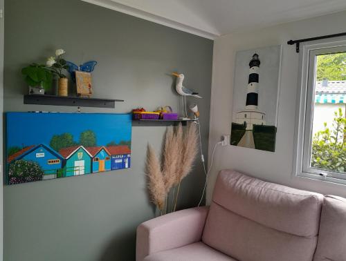 a living room with a chair and a picture of a lighthouse at mobil-home 468 in Saint-Georges-dʼOléron