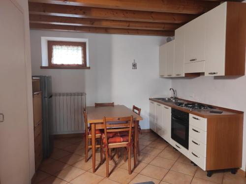 una cucina con tavolo, sedie e fornelli di Grazioso appartamento con giardino e posto auto a Belluno