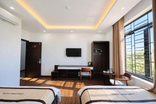 een hotelkamer met twee bedden en een bureau bij Sunflower Hotel Mộc Châu in Mộc Châu