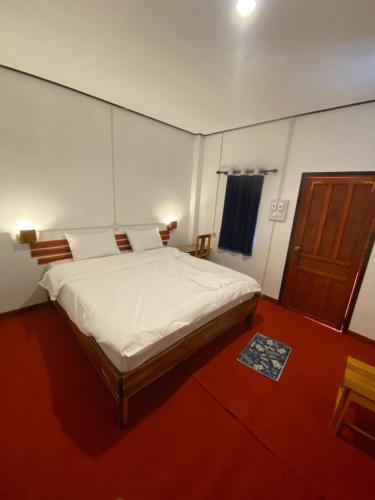 a bedroom with a large bed and a wooden door at Thavisok Guest House in Nongkhiaw