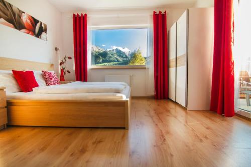 Schlafzimmer mit einem Bett und einem Fenster mit roten Vorhängen in der Unterkunft Oscar & Sons Apartments in Piesendorf