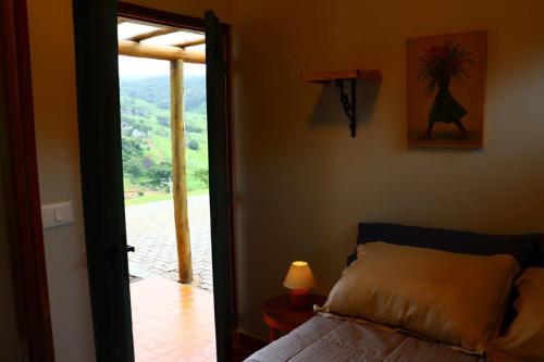 a bedroom with a bed and a door leading to a porch at Aura dos Ipês in Paraisópolis