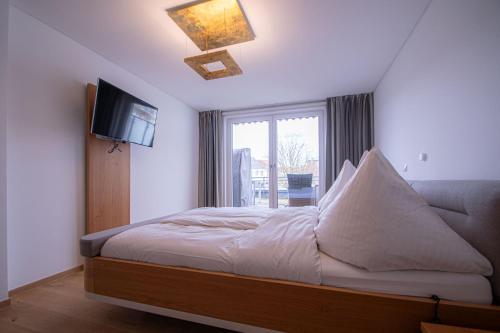 a bedroom with a bed and a tv and a window at Traumwohnung in Norderney