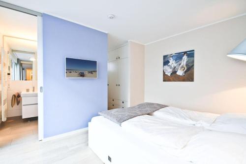 a bedroom with a white bed and a blue wall at Ferienwohnung Meeresrauschen in Norderney