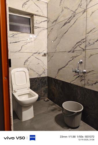a bathroom with a toilet and a marble wall at JOHNs' Paradise - Homestay in Cochin