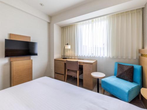 a hotel room with a bed and a desk and a chair at Nishitetsu Hotel Croom Hakata in Fukuoka