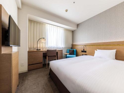 a hotel room with a bed and a desk at Nishitetsu Hotel Croom Hakata in Fukuoka