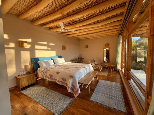 een slaapkamer met een bed en een groot raam bij The Indus River Camp in Leh