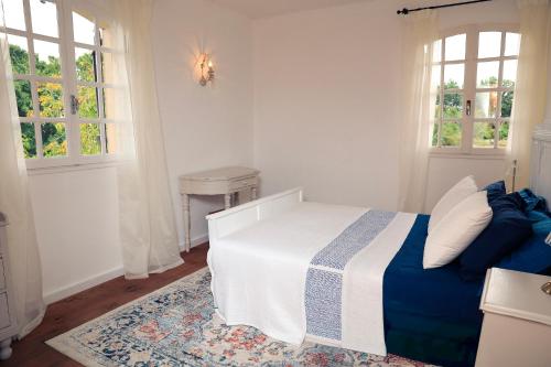 una camera da letto con un letto blu e bianco e due finestre di Pure Gardères a Monlezun