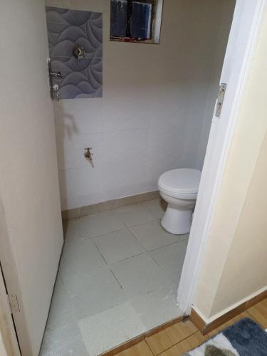a bathroom with a toilet and a tile floor at EsMash Studio Machine lanet Nakuru in Nakuru