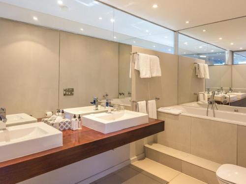 een badkamer met twee wastafels en een grote spiegel bij Infinity Self Catering Apartments in Bloubergstrand