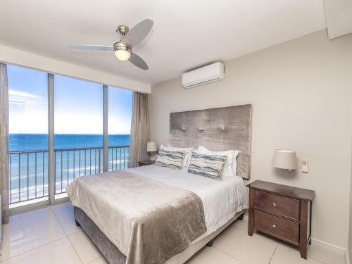 een slaapkamer met een bed met uitzicht op de oceaan bij Infinity Self Catering Apartments in Bloubergstrand