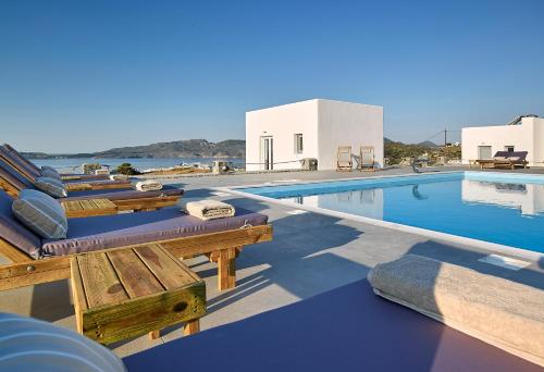 een zwembad met ligstoelen naast een zwembad bij Lithos Luxury Rooms (Adults Only) in Adamas