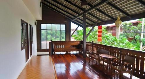 a porch with benches and a table and windows at Nan Lanna Hotel in Nan