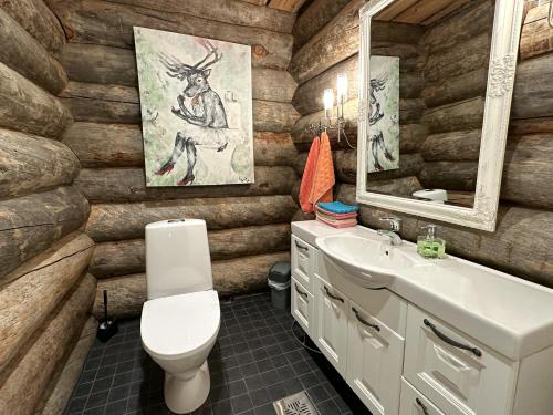 ein Badezimmer mit Holzwänden, einem WC und einem Waschbecken in der Unterkunft Napapiirin Järvilomat in Rovaniemi
