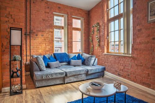 a living room with a couch and a brick wall at City Centre 2-Bed, 2 Balconies, 65 Inch TV, Free Parking, Coffee Machine, Netflix in Leicester