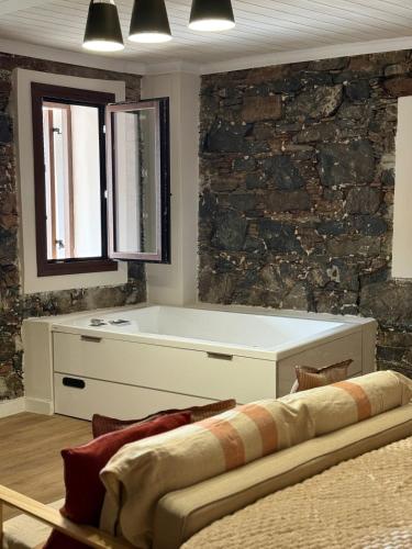 a bath tub in a room with a stone wall at Aprosmeno House 6 in Agros
