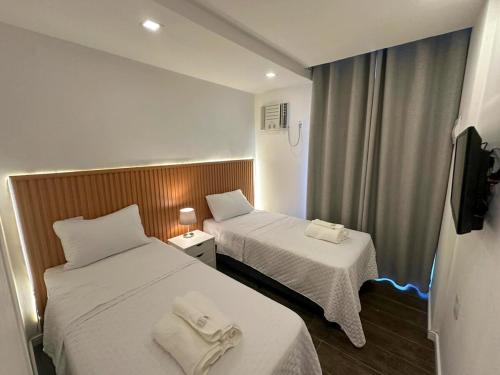 a hotel room with two beds and a tv at Vila em Laranjeiras in Rio de Janeiro