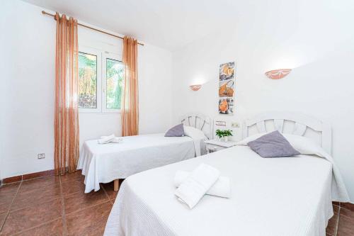 due letti bianchi in una stanza con una finestra di Villa Nispero a El Tosalet