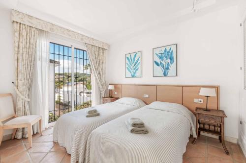 a white bedroom with two beds and a window at Villa Oceana in Manilva