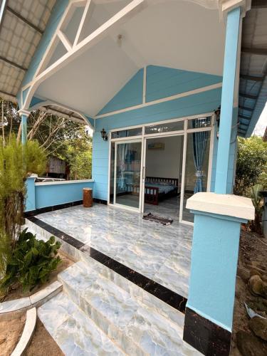 a patio with a blue house with glass doors at Garden Hostel Koh Rong in Koh Rong Island