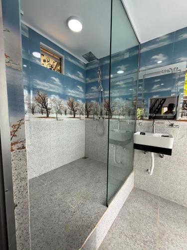 a bathroom with a glass shower with a sink at Bliss Lodge Diyaluma in Demodara