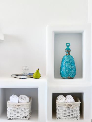 a white shelf with baskets and a blue vase at Lithos Luxury Rooms (Adults Only) in Adamantas