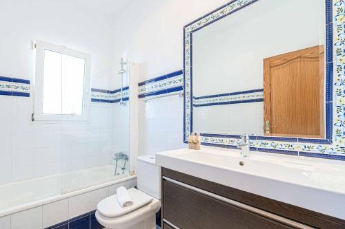 un bagno con lavandino, WC e specchio di Villa Pera a El Tosalet