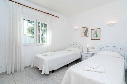 due letti in una stanza bianca con una finestra di Villa Pinya a El Tosalet
