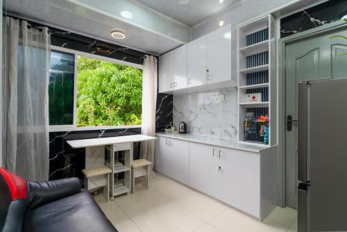 eine Küche mit weißen Schränken, einem Fenster und einem Waschbecken in der Unterkunft Naseema Hiya - Central Ukulhas Residences in Ukulhas