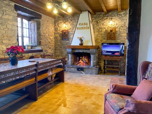 een woonkamer met open haard en tv bij Casa Rural Masión de Egüés in Elcano